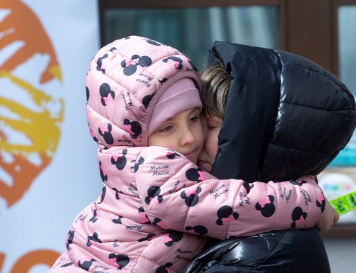 A woman hugs a young girl