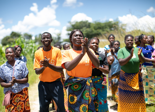A group of people walking along a road smiling and clapping