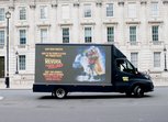 A truck drives in front of a UK parliamentary building with the slogan 'Dear Prime Minister, Back to the Future is a film, not foeign policy Reverse the Rollback. don't take women's rights back by decades. Protect funding for women and girls.