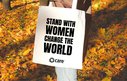 Woman holding a tote bag in the autumn leaves with 'stand with women change the world' on it